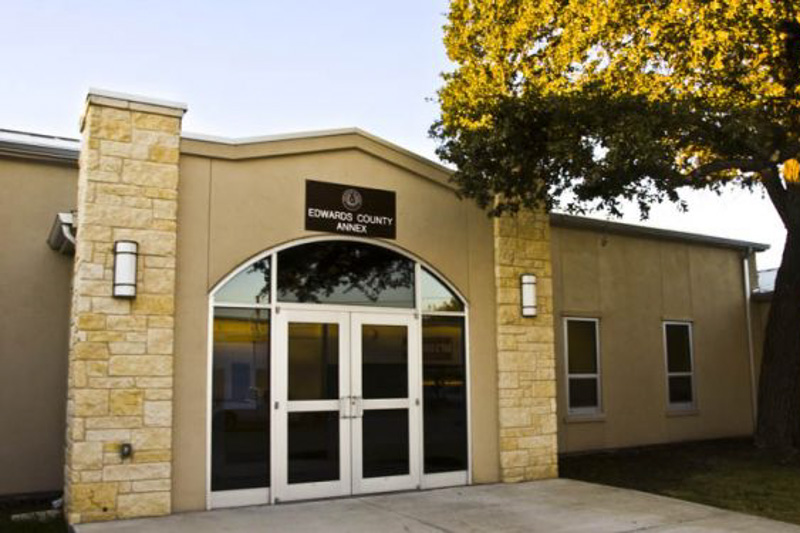 Front entrance of the Edwards County Annex, with stone columns and a sign above the glass doors